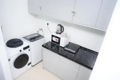 a white kitchen with a stove and a microwave at Kuala Lumpur Kids Friendly Playground Bunk Bed in Kuala Lumpur