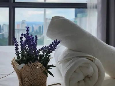 a towel sitting next to a vase with purple flowers at Skyline view in Bukit Bintang The Robertson 42f in Kuala Lumpur
