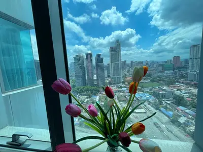 a vase filled with flowers sitting in a window at Mercu Summer Suite KLCC by Kuminshu in Kuala Lumpur