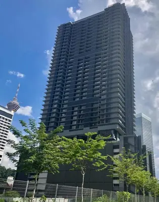 a tall building with a tree in front of it at Anggun Residence Serviced Suites By BedStay in Kuala Lumpur
