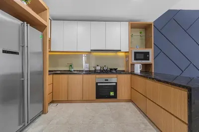 a large kitchen with wooden cabinets and a refrigerator at Anggun Residence Serviced Suites By BedStay in Kuala Lumpur