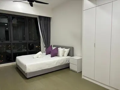 a bedroom with a bed with white sheets and purple pillows at The Ooak Suites by Bamboo Hospitality in Kuala Lumpur