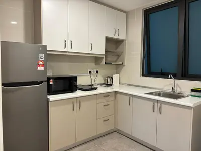 a kitchen with white cabinets and a stainless steel refrigerator at The Ooak Suites by Bamboo Hospitality in Kuala Lumpur