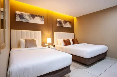two beds in a hotel room with yellow walls at Raissa Boutique Hotel in Kuala Lumpur