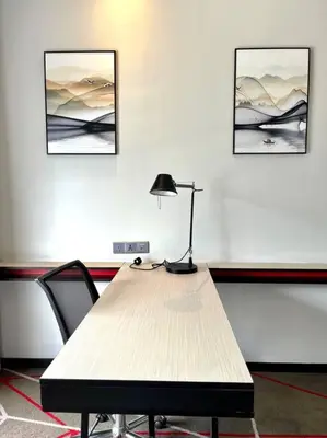 a desk with a lamp and two pictures on the wall at #173 M101 Dang Wangi KLCC View Pool By Livin in Kuala Lumpur