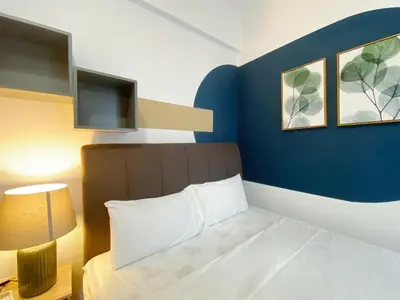 a bedroom with a bed and a blue wall at The Colony By Infinitum By Awesomestay in Kuala Lumpur