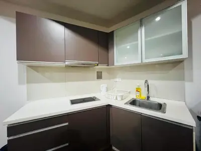 a kitchen with brown cabinets and a sink at Regalia Residence And Suites By The Relaxstay in Kuala Lumpur