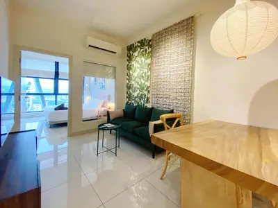 a living room with a green couch and a bedroom at Arte Mont Kiara By The Relaxstay in Kuala Lumpur