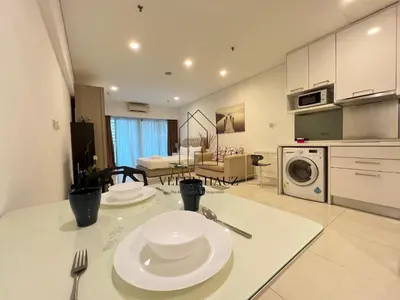 a kitchen and living room with two plates on a table at Mercu Summer Suites KLCC by Veedu Hauz in Kuala Lumpur