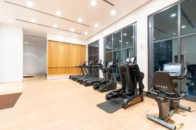 a gym with a row of treadmills and ellipticals at Harmony Luxury Suites At Lucentia Bukit Bintang City Center in Kuala Lumpur